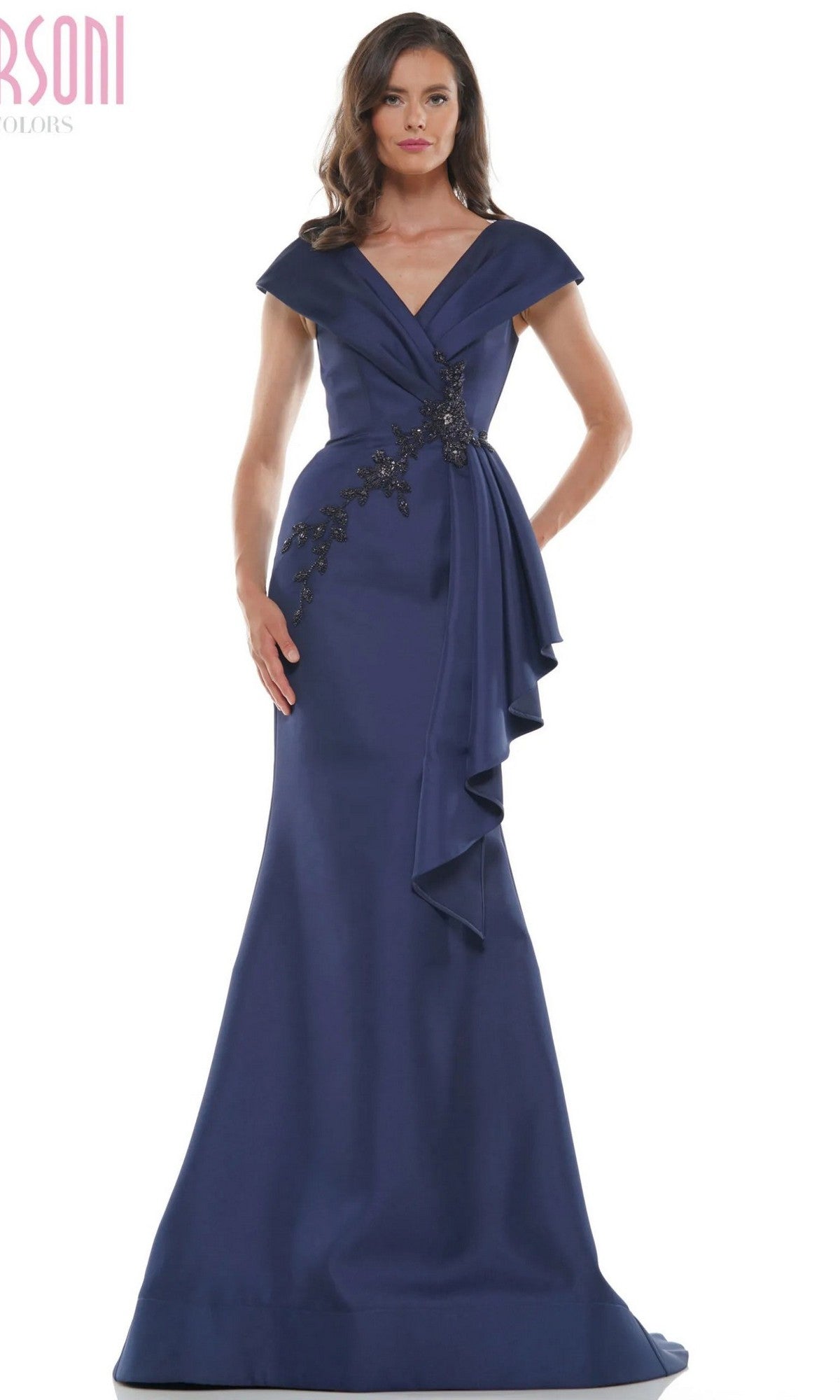 A woman wearing the Marsoni MV1086, a floor-length navy formal dress with an off-the-shoulder neckline, draped details, floral and beaded waist embellishments, and a graceful trumpet silhouette.
